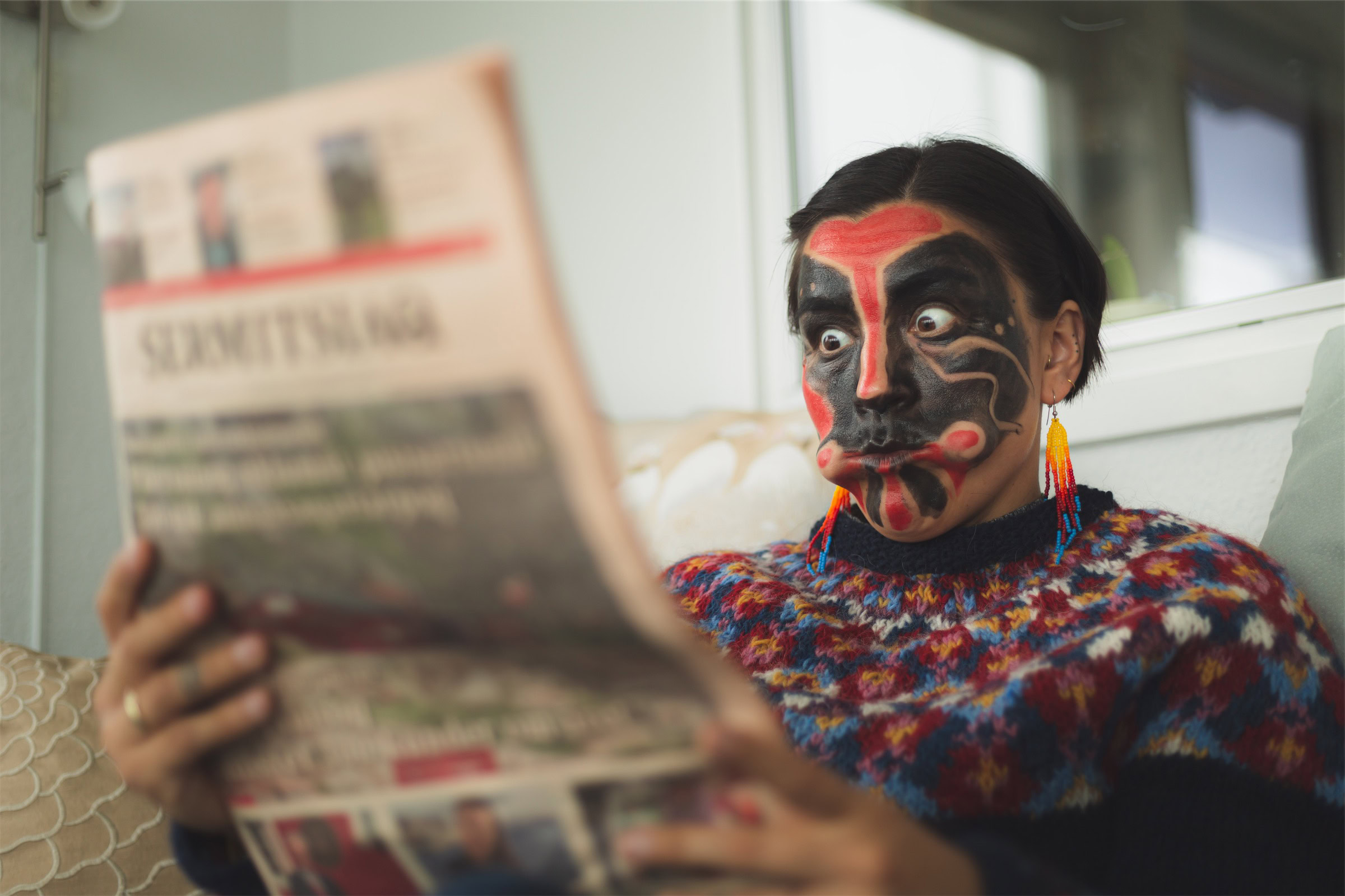 Greenlandic mask dancer reading the newspaper. Photo - Magnus Biilmann Trolle, Visit Nuuk