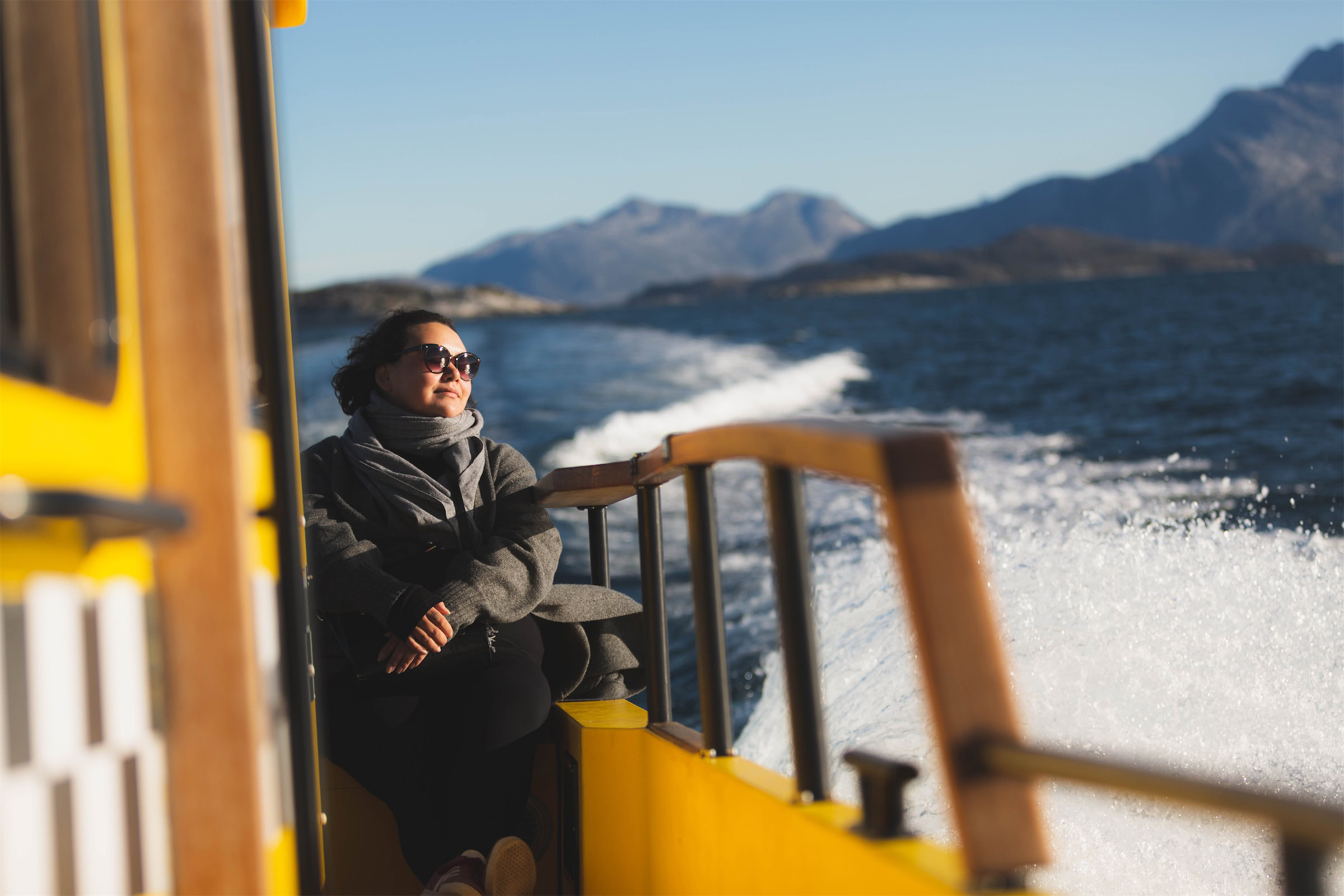 Woman relaxing on yellow boat during sunset. Photo - Magnus Biilmann Trolle, Visit Nuuk